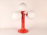 une lampe de table rouge sur laquelle sont posées trois boules blanches