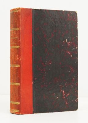 an old red and black book sitting on top of a white surface