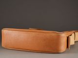 tan leather belt bag on grey surface with grey background