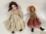 two dolls sitting next to each other on a white surface