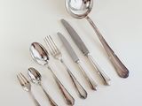 a lot of silverware on the table with a spoon and knife