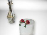 a vase with flowers in it next to a pair of earrings