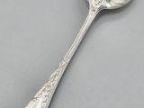 a silver spoon with a spoon handle on a gray surface