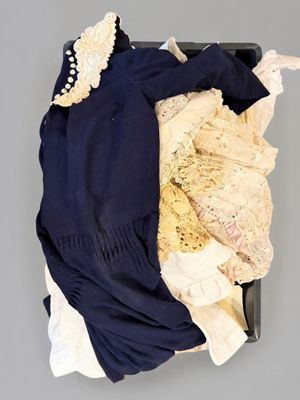 une valise noire contenant des vêtements, avec un chapeau posé dessus