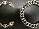 un gros plan sur deux bracelets argentés posés sur une surface noire