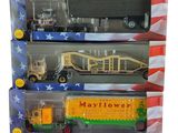 cinq camions miniatures dans une vitrine, sur fond blanc