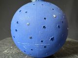 a blue ornament with stars on it sitting on a rock