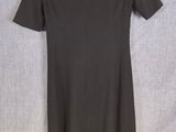 a black dress hanging on a hanger on a wall