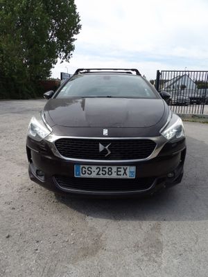 the front of a black car parked in a parking lot next to a fence