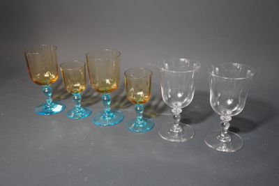 Plusieurs verres à vin de différentes couleurs sont alignés sur une surface grise