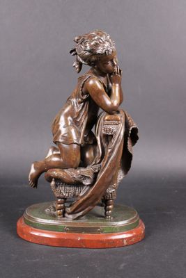 an antique bronze statue of a woman sitting on a chair