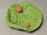 deux tomates posées sur un plat en forme de feuille, sur une table