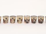 several shot glasses with different designs are lined up on a white surface