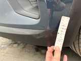 a person holding a ruler in front of a car