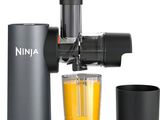 a juicer with a glass of orange juice next to it