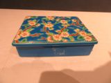une boîte bleue décorée de fleurs, posée sur une table