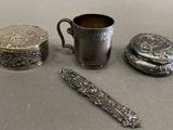 a silver cup, spoon, and other silver items on a table