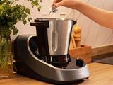 a woman putting something in a blender on a kitchen counter