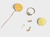a gold ring, a gold earring, and a pair of earrings on a white surface