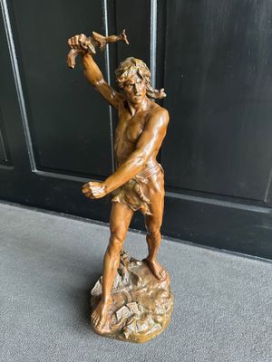 statue en bronze représentant un homme tenant un oiseau sur un rocher