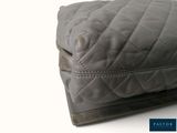 a grey quilted bag sitting on top of a white table