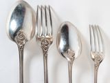 five silver spoons and a fork on a white table