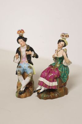 two figurines of a man and a woman sitting on a rock