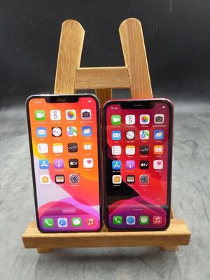 Deux iPhones sont posés sur un support en bois, sur une table.