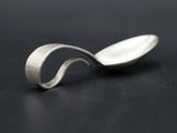 a close up of a spoon with a curved handle on a black surface