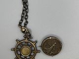 un gros plan d'une pièce de monnaie et d'un collier posés sur une surface blanche
