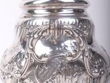 a silver pot sitting on a stand on a white surface