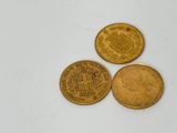 trois pièces d'or superposées sur une surface blanche