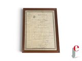 an old document is hanging on a wall next to a plaque