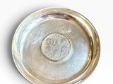 a silver plate on a white surface with a coin in the middle