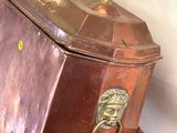 une grande boîte en cuivre surmontée d'une tête de lion