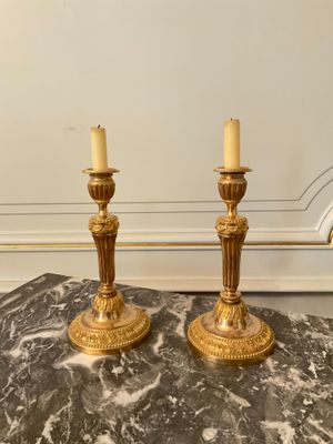 a pair of brass candlesticks on a marble table