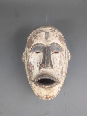une image d'un masque en bois accroché au mur