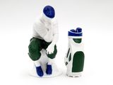 a figurine of a man sitting on a toilet with a golf bag next to it