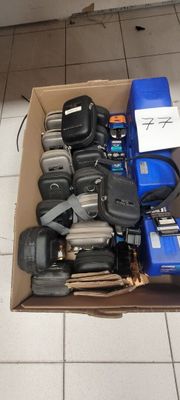 une boîte en carton remplie de téléphones portables de toutes sortes, posée sur un sol carrelé