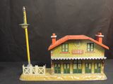 a small yellow and green building with a red roof