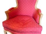 une image représentant une chaise rose aux finitions dorées, avec un coussin rouge