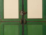 an old green double door with two glass panels and a metal handle
