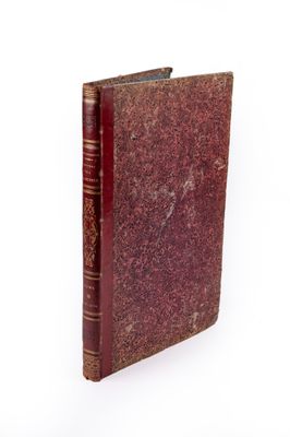 un vieux livre à la couverture rouge posé sur une surface blanche