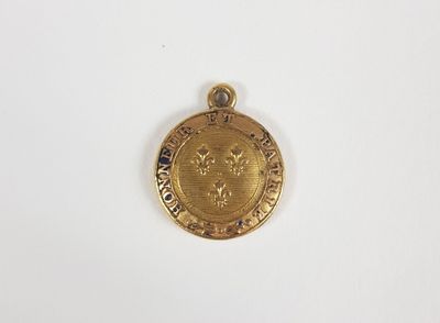 une petite médaille en or sur laquelle est représenté un lion
