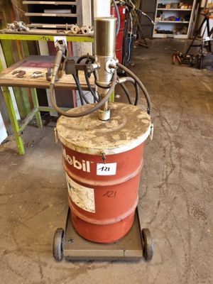 un fût rouge posé sur une charrette dans un garage
