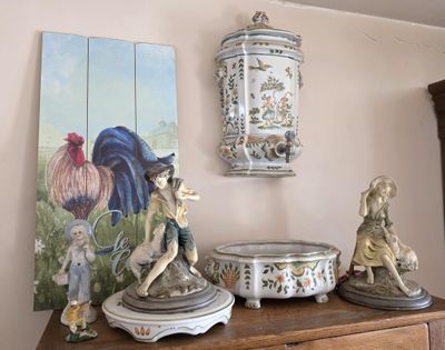 un tableau accroché au mur au-dessus d'une commode sur laquelle sont posées des statuettes