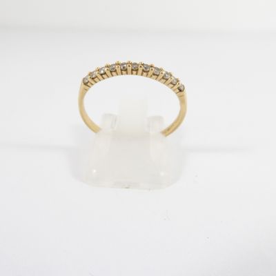 une bague en or jaune sertie de cinq diamants sur fond blanc