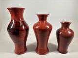 three red vases sitting next to each other on a table