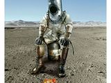 a man in a space suit sitting on a chair in the desert