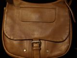 brown leather handbag sitting on a black surface with a black background